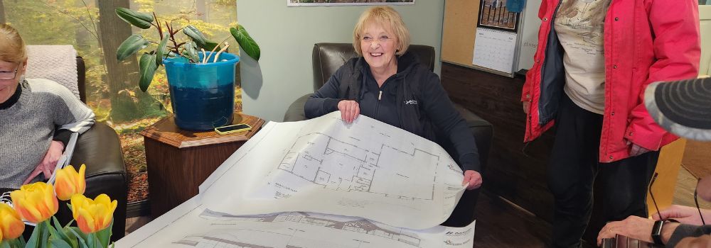 A woman holding a blue print of the new rehab center she's building.