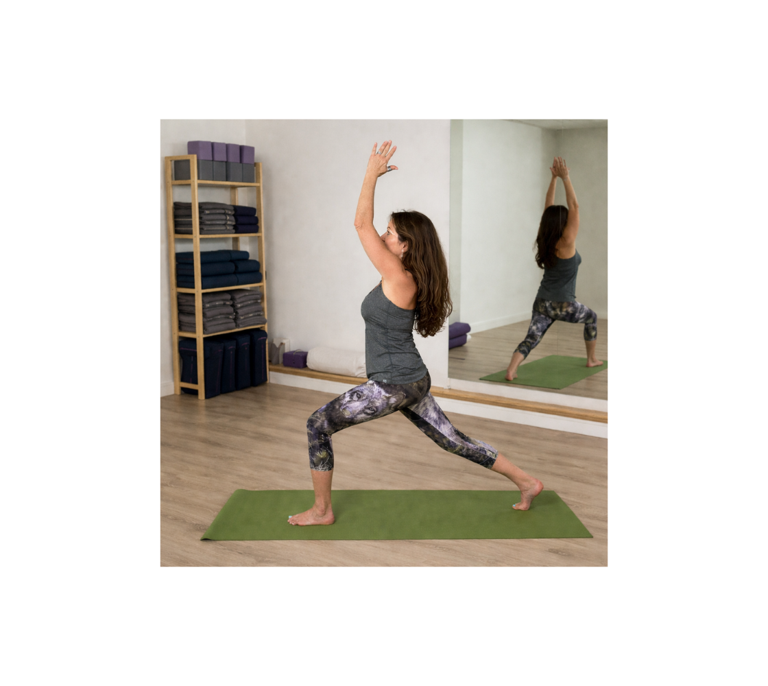 Woman practicing yoga in a home setting wearing a pair of capri leggings with a wolf design.
