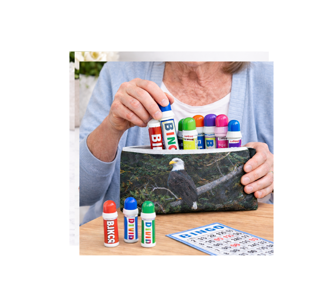 Elderly Woman holding a bag of bingo markers with a zippered pouch design, featuring an bald eagle, on a wooden table.