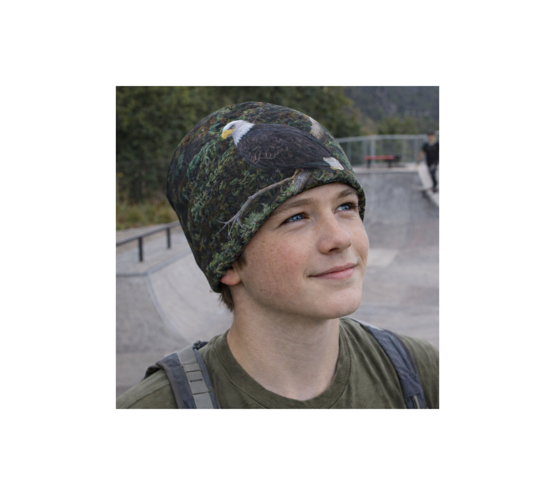 A young boy at skat park wearing a bamboo-lined beanie with an image of a bald eagle design with a green background.
