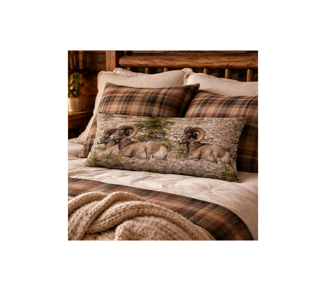 Decorative long throw pillow cover with a bighorn rams design on a bed.