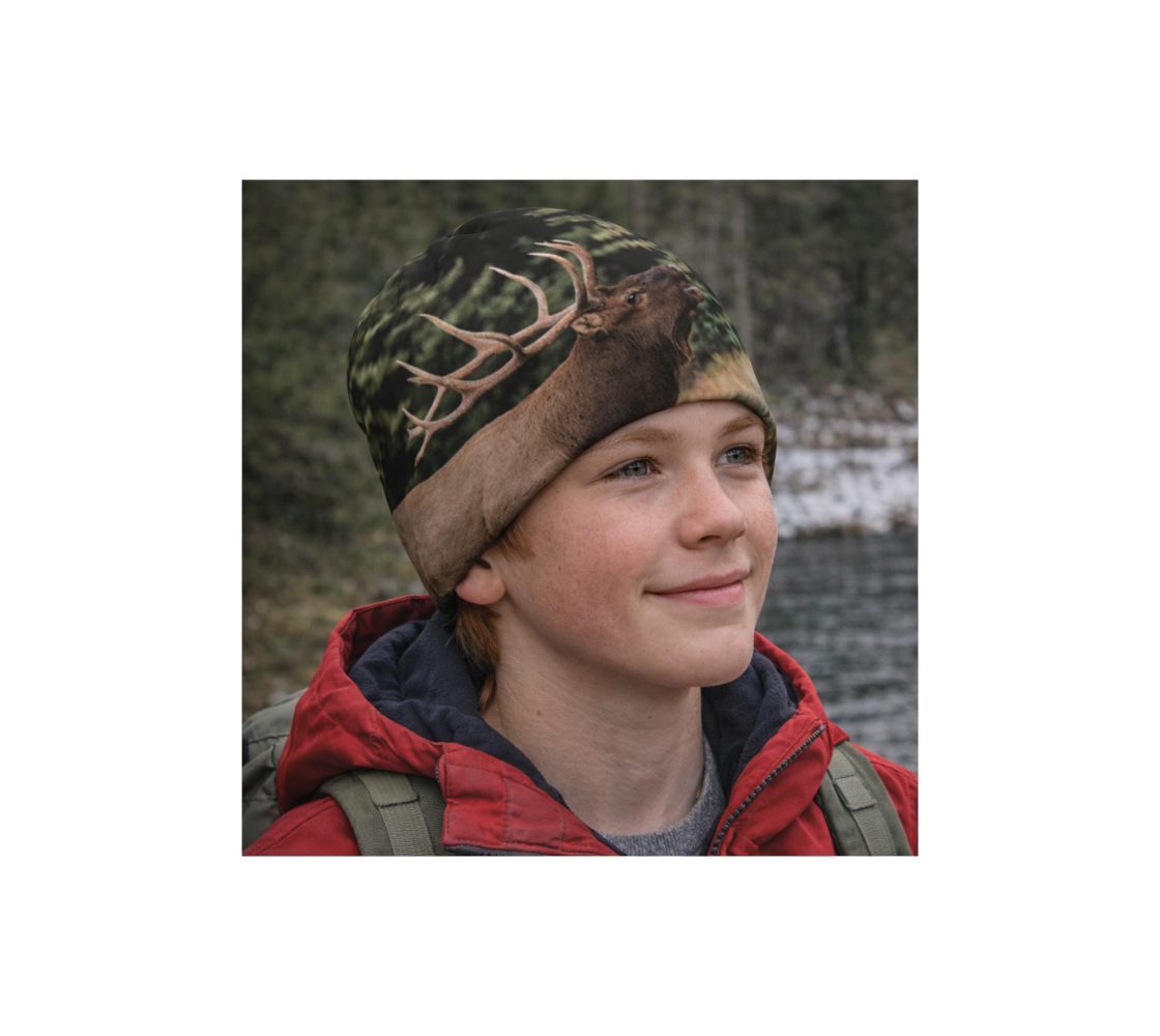 A young boy standing by river wearing a bamboo-lined beanie with an image of bull elk design with a green background.