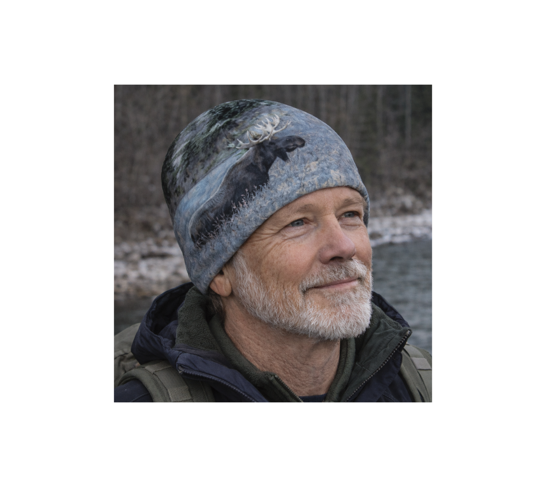 A man standing by river wearing beanie with a image with bull moose.