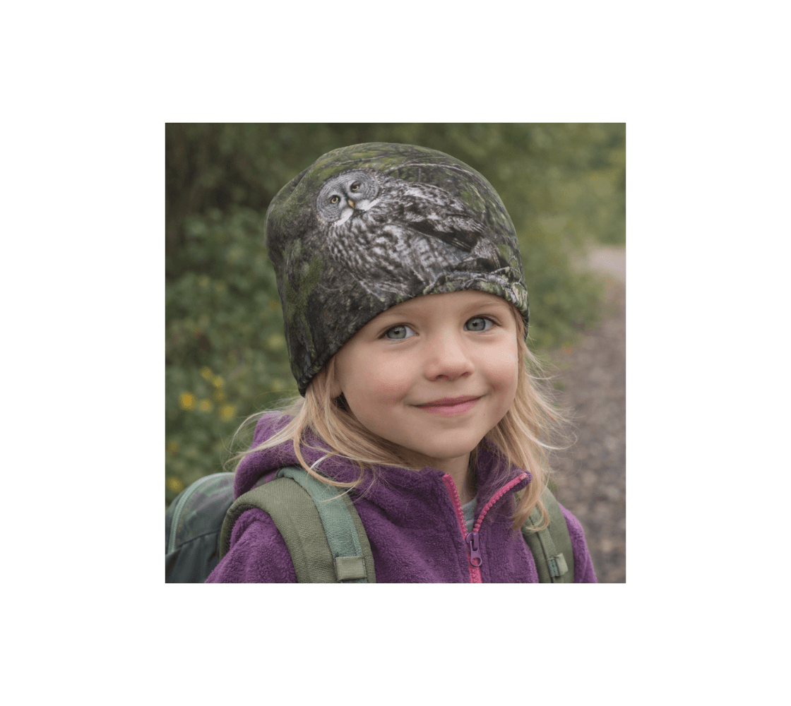 A young girl wearing a great gray owl bamboo-lined beanie from our wildlife photography standing in nature.