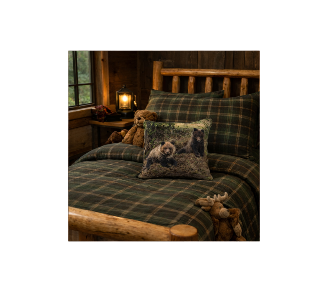 Bed with plaid bedding and grizzly bear cubs-themed throw pillow cover in a rustic cabin setting.
