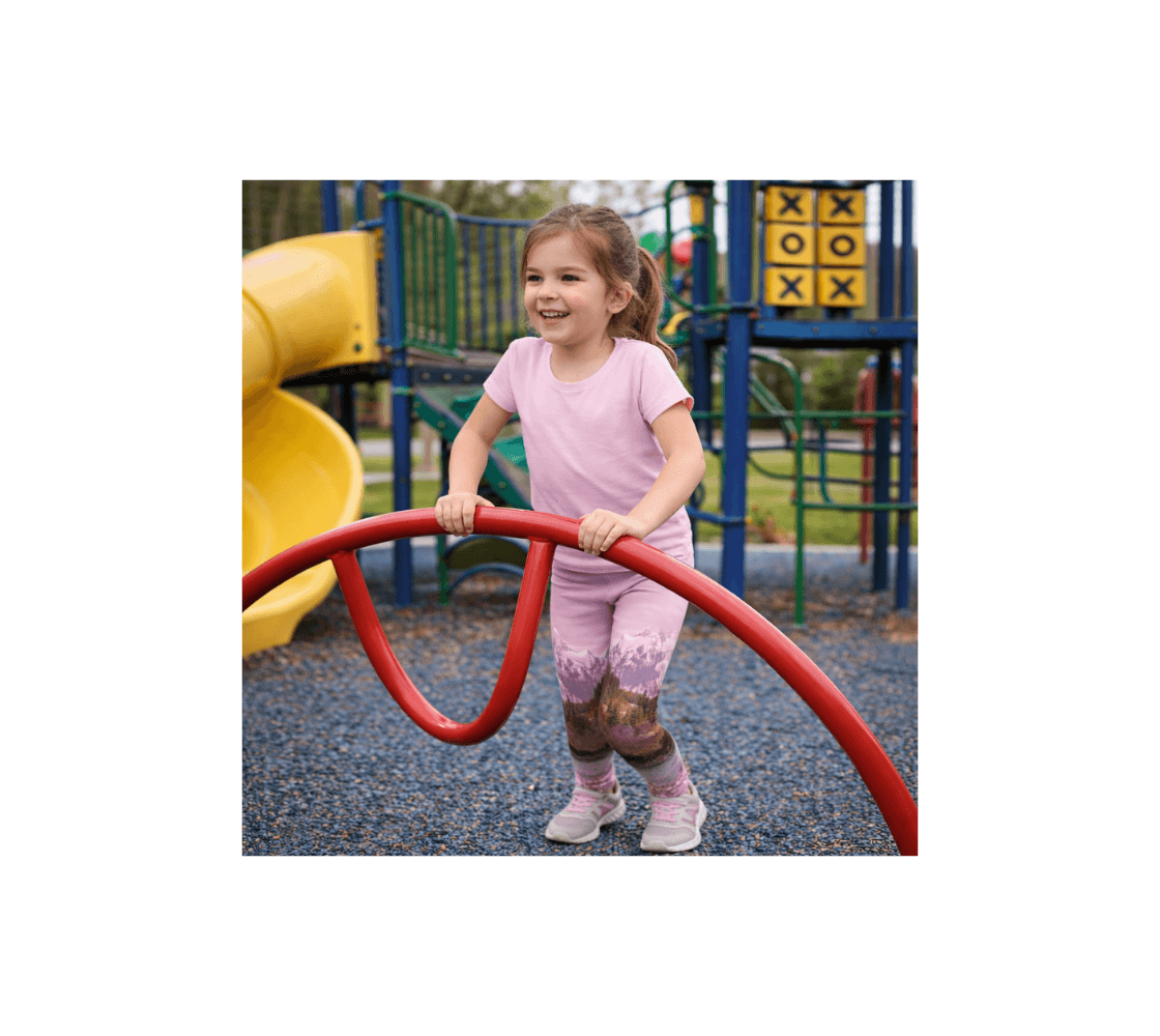 A youth girl playing wearing a pair of pink mountain sunset youth leggings from our nature photography at a playground.