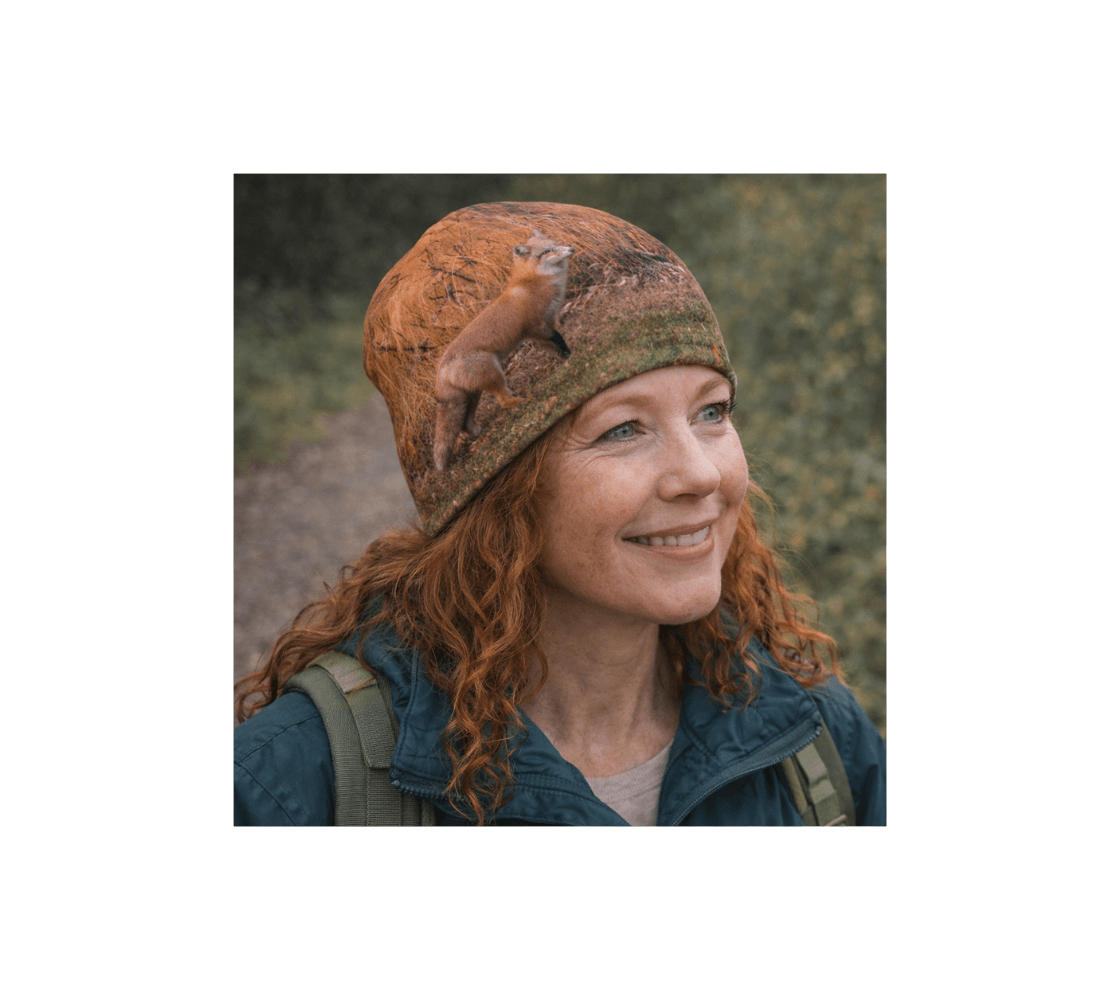 A woman with red hair wearing a red fox bamboo-lined beanie from our real wildlife photography standing in forest.