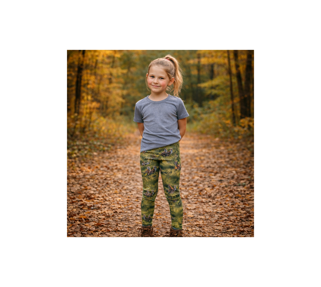 A young girl standing wearing pair of red fox kits youth leggings from our Canadian Wildlife photography on a path way in a forest.