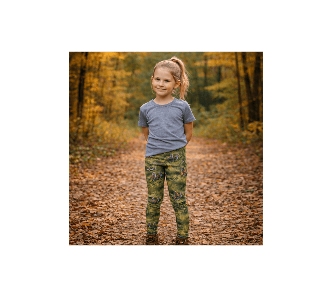 A young girl standing wearing pair of red fox kits youth leggings from our real Canadian Wildlife photography on a path way in a forest.