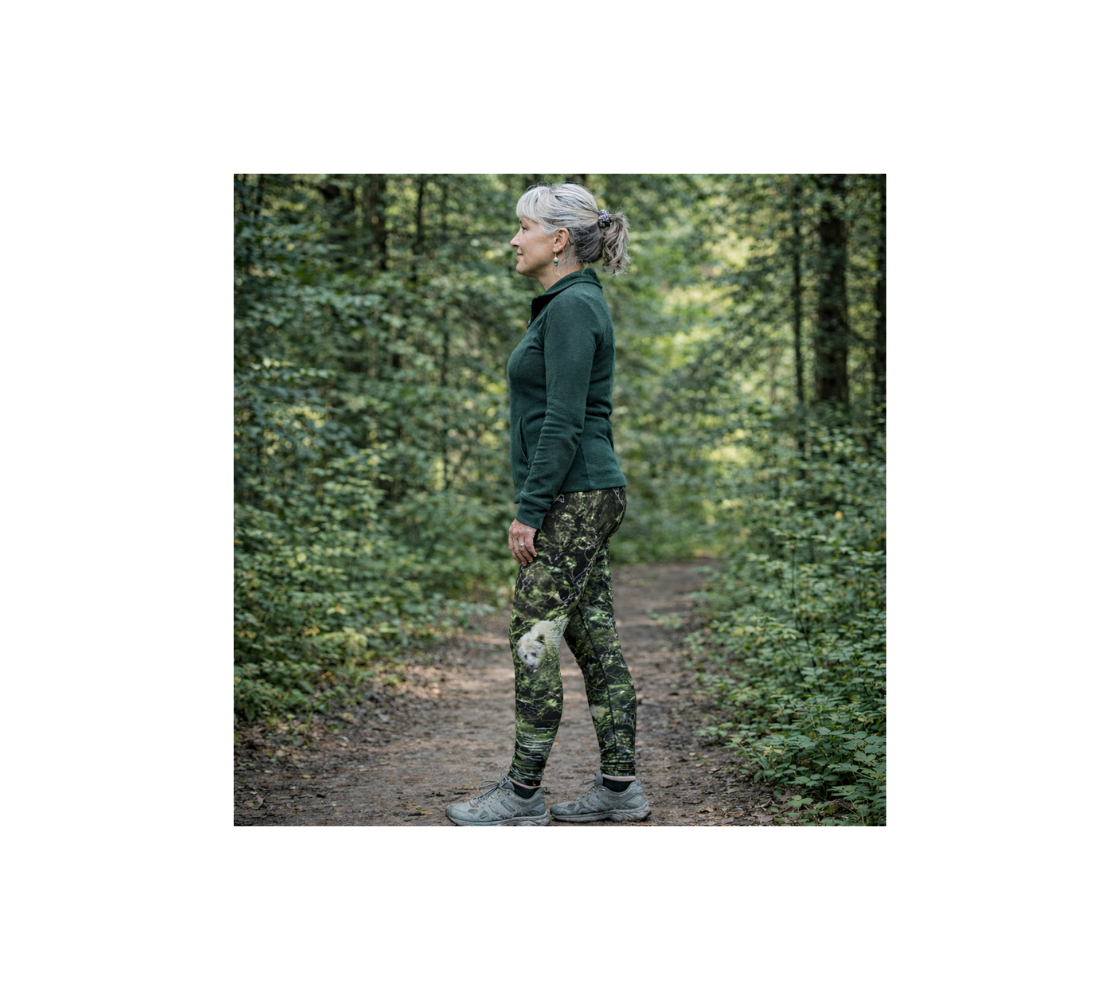 A woman standing in the forest wearing a pair of spirit bear classic leggings from our wildlife photography.