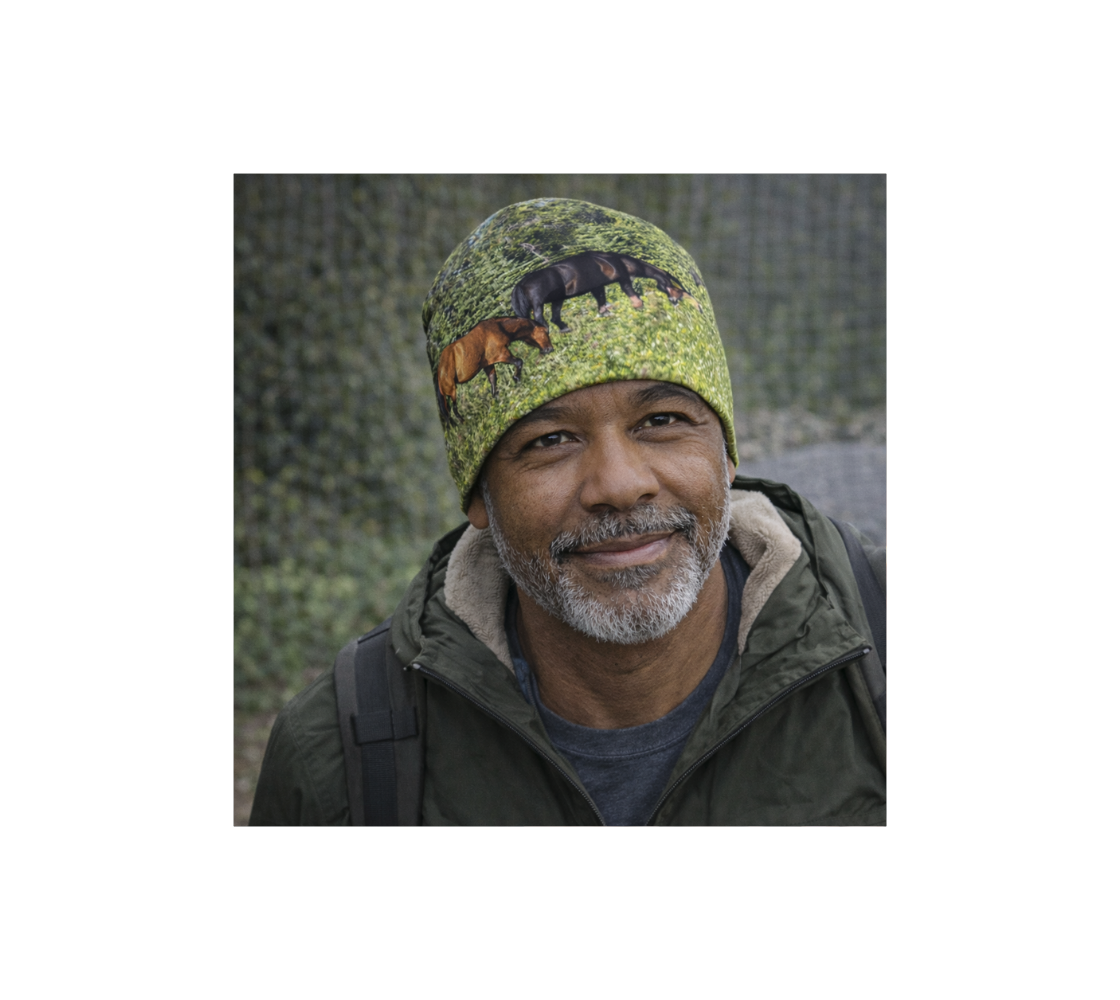 A man standing in nature wearing a bamboo-lined beanie with an image of wild horses design with a green background.