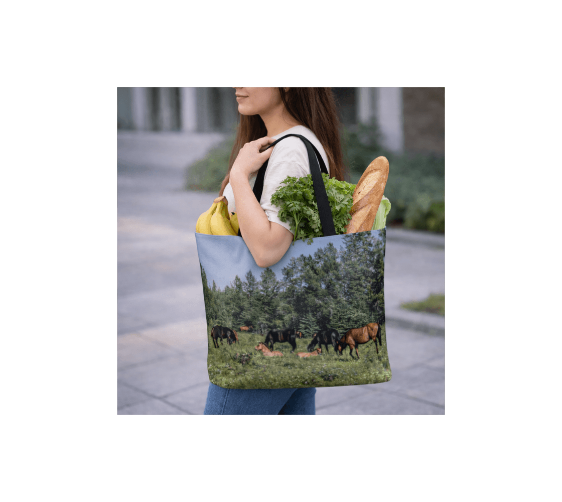 A woman carrying a band of wild horses large reusable tote bag from our wildlife photography with groceries inside it.