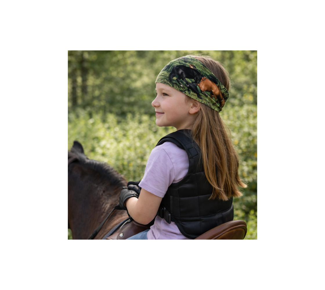Child riding a horse wearing headband with a image of wild horses in a forest setting.