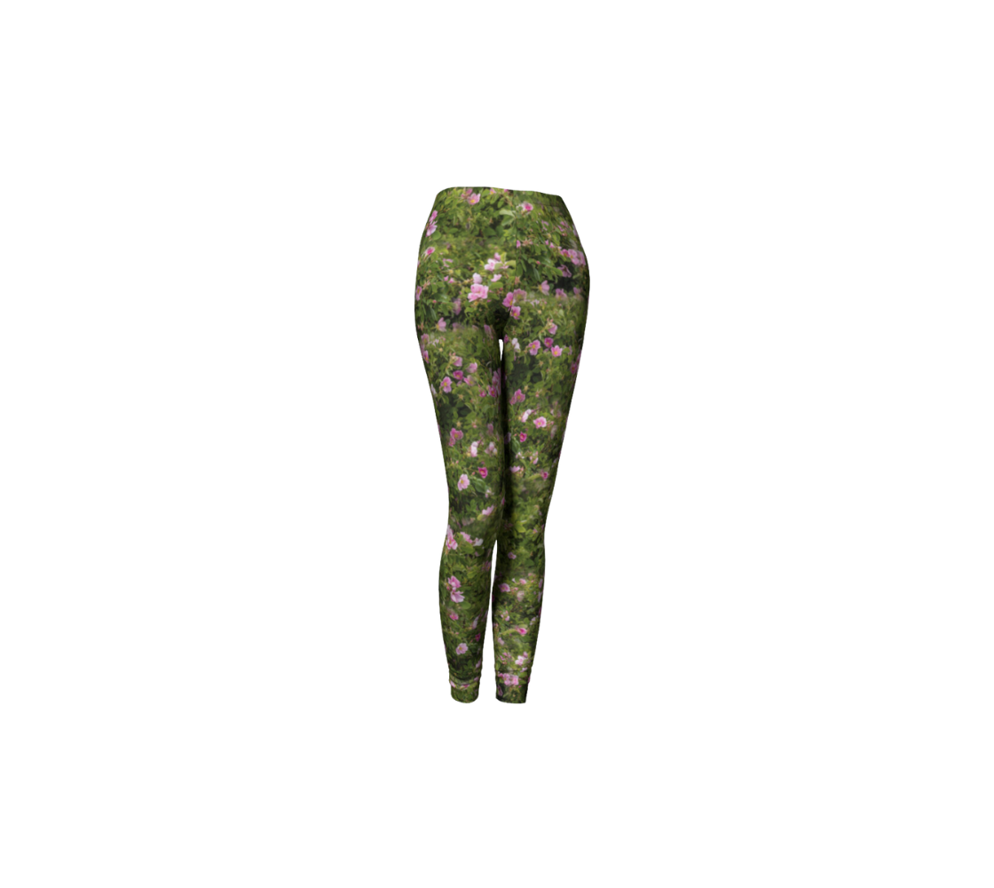 This is a front profile of a pair of classic leggings featuring a photo of wild roses on each leg, with a 1.5 inch wide elastic waistband. The background is a collage of green wild rose bushes with pink flowers and buds througout that have yellow centers.