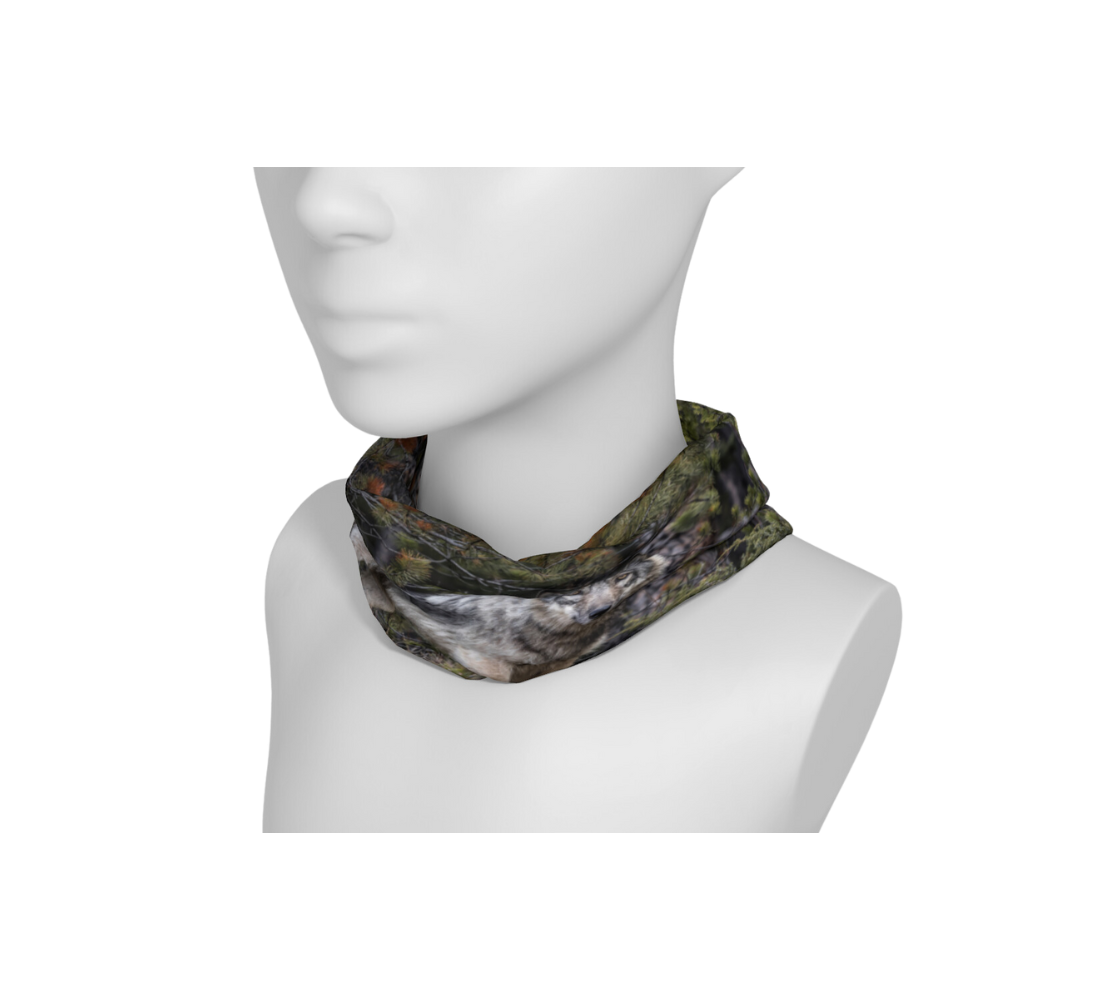 This is an image of a photo of a grey wolf on a head and neck band on a mannequin worn as a neckdband. The background is of evergreen trees and grey bushes, while the wolf head is full and fluffy in various tones of grey and white with beautiufl yellow eyes looking directly at you.