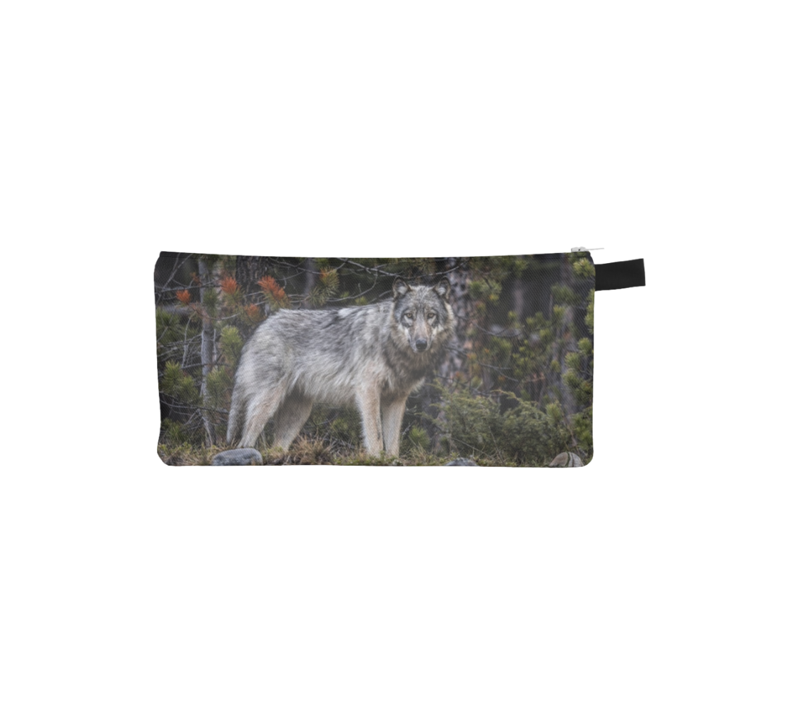 This is a side profile photo of a wolf on a canvas zippered pouch. The background is of evergreen trees and grey bushes, while the wolf's coat is full and fluffy in various tones of grey, white and black with beautiufl yellow eyes looking directly at you.