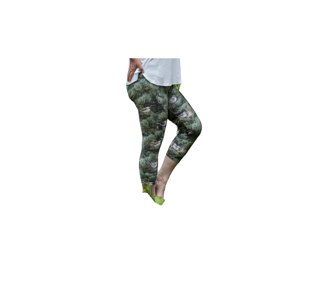 This is an image of a side profile of a lady wearing a pair of 3/4 length capris, featuring a photo with green tree boughs in the background with a repeating photo collage of the four different chickadees of Western Canada in their colorful black, brown, white, rust and grey tones.
