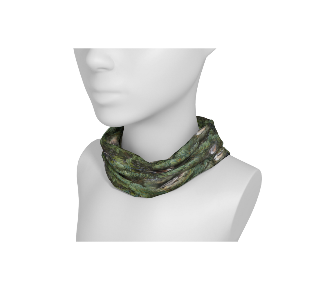 This is an image of a photo collage of chickadees on a head and neck buff worn as a neckband on a mannequin. The fabric print is of green tree boughs in the background with a repeating collage of the four different chickadees of Western Canada in their colorful black, brown, white, rust and grey tones.