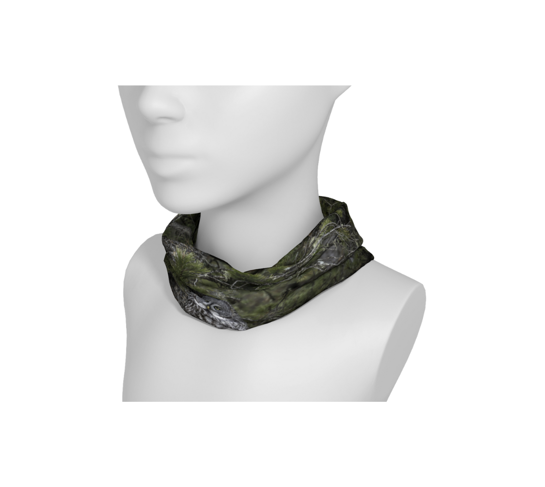 A mannequin head with a head and neck buff wrapped around the neck with an image of a great gray owl design with a green background.