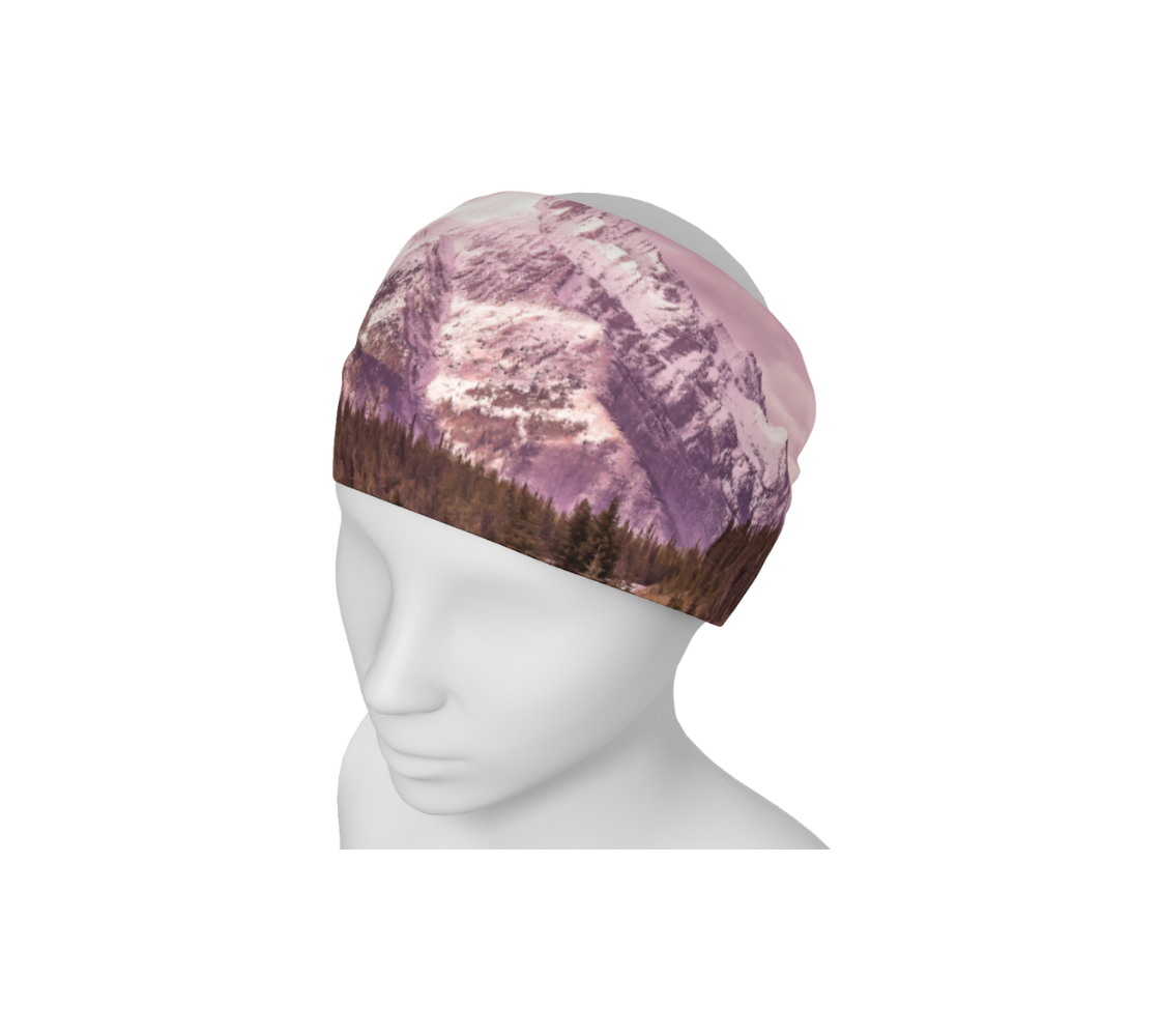 This is an image of a photo of a pink mountain scene on a head and neck band on a mannequin worn as a headband. The scene is of a snow covered mountain in the far distance with a meandering stream winding its way through the fall colored willow and forest of evergreen trees towards the mountain. A special filter used when taking this photograph created an over all pink hue to the image that really accentuated the sunset light at the time.