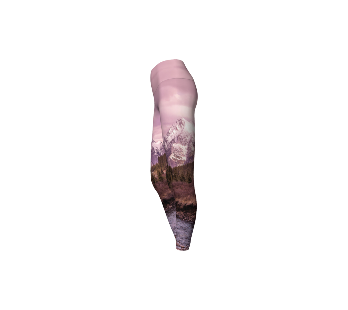 This is a side profile of a photo of a pink mountain scene on a pair of yoga leggings, with a 4.5 inch wide waistband. The image is of a snow covered mountain in the far distance with a meandering stream winding its way through the fall colored willow and forest of evergreen trees towards the mountain. A special filter used when taking this photograph created an over all pink hue to the image that really accentuated the sunset light at the time.