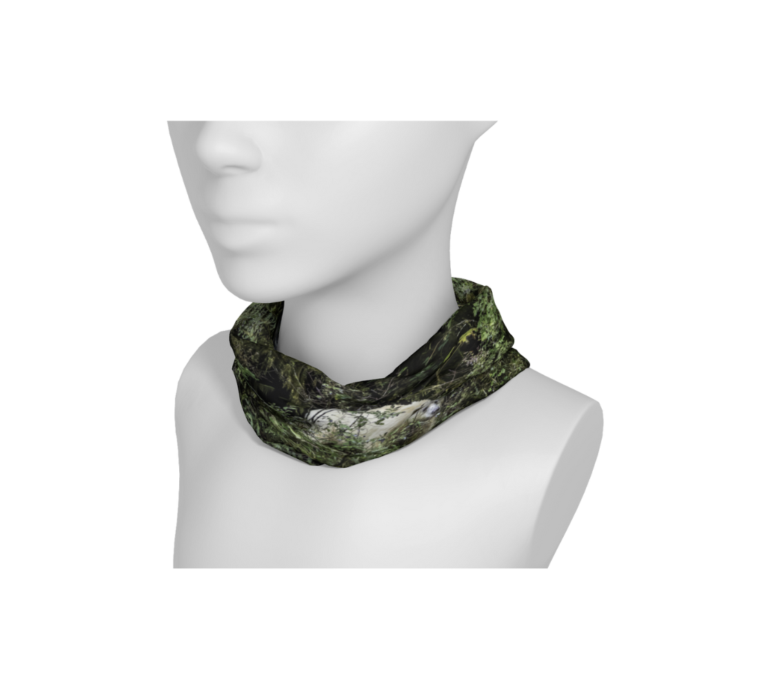 A mannequin head with a head and neck buff wrapped around the neck with an image of a spirit bear design with a green back ground.