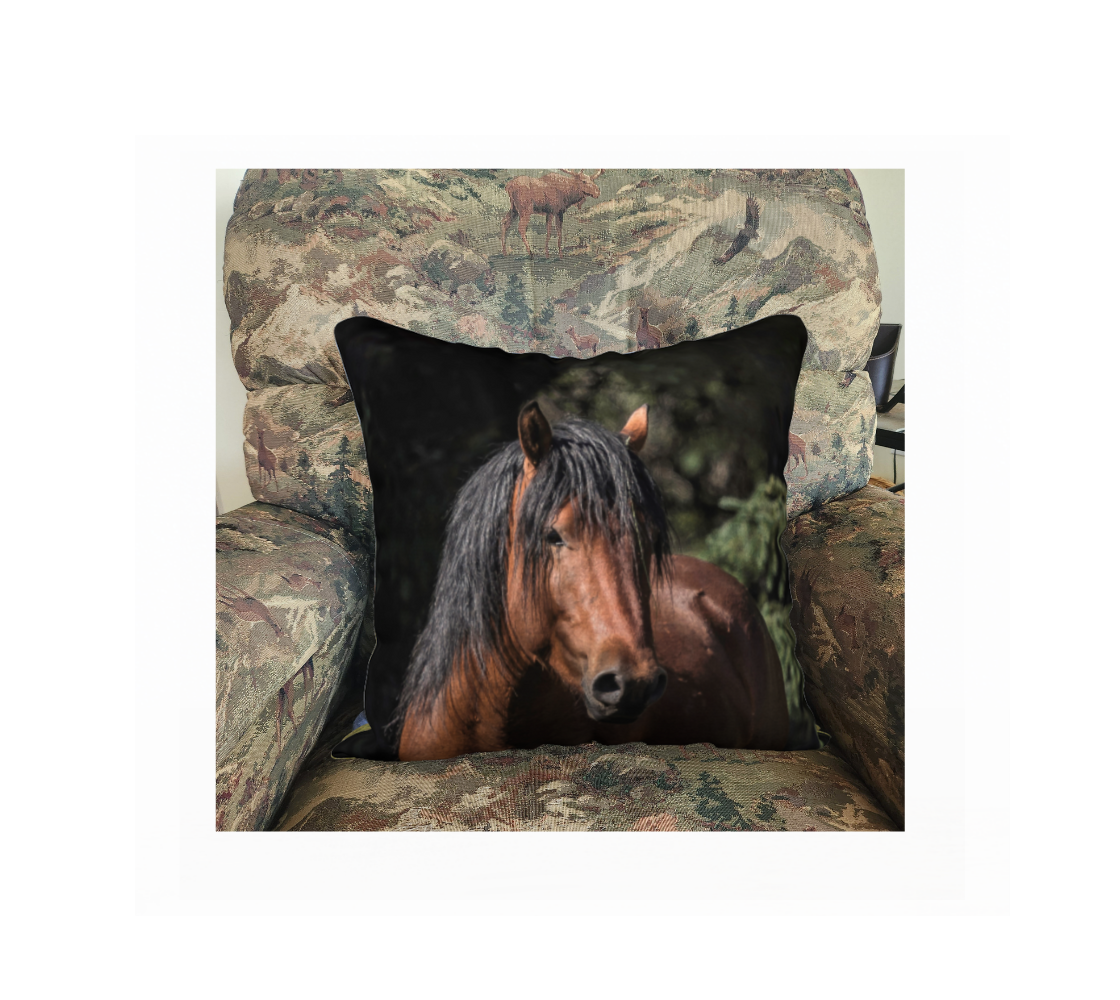 This 18 x 18 inch plush velveteen cushion cover features a photo of a wild stallion horse head portrait with a chestnut brown head and black mane. The cushion cover background is black and green evergreen trees. This image is of a cuhion cover on a pillow form in a chair.