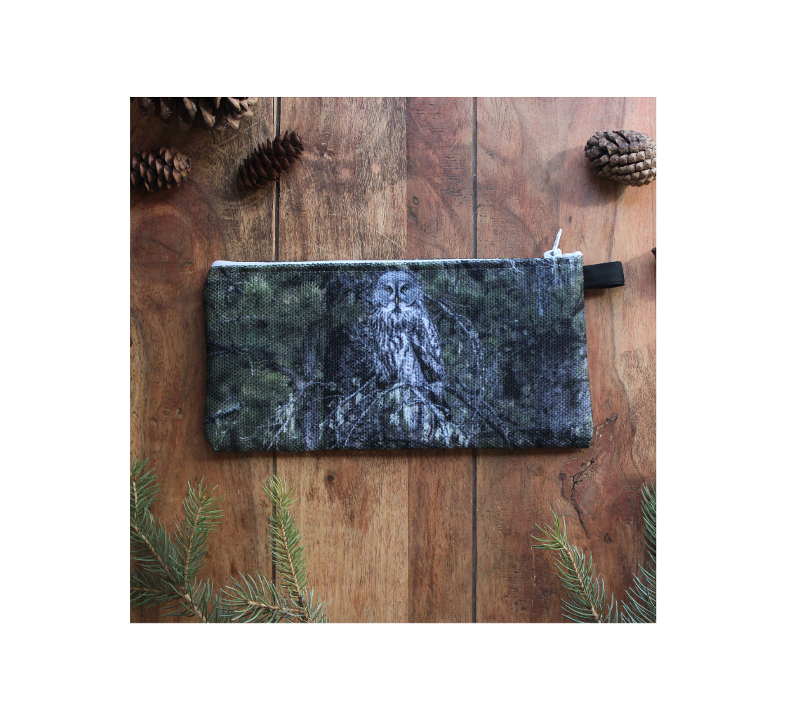 Durable double sided 9” x 4” canvas zippered pouch featuring real images of great grey owl in the spruce a tree.