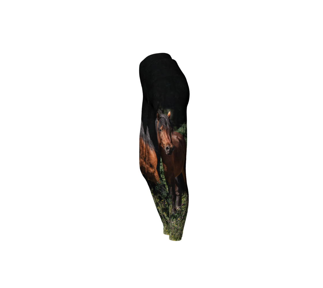 This is a side profile of a pair of yoga leggings featuring a photo of a wild stallion on each leg, with a 4.5 inch high waistband. The background is dark green/black at the top with green grass at the bottom, with an image of a chestnut brown wild horse with a black mane and tail.