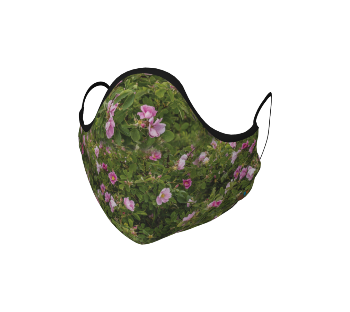 This is a face mask with black ties that is a photo of a collage of green wild rose bushes with pink flowers and buds througout that have yellow centers.