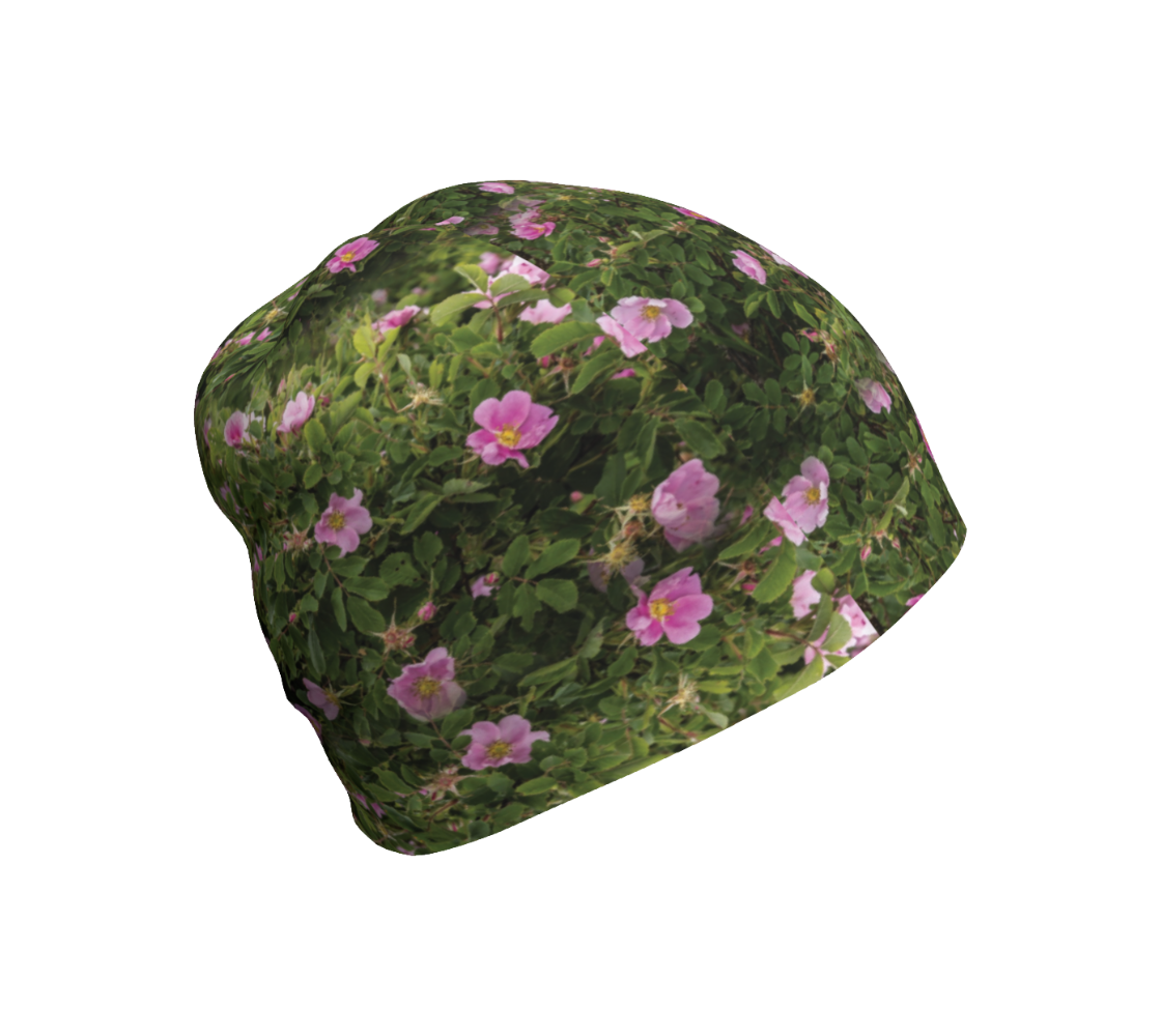 This is a photograph of pink wild roses on a beanie. The beanie is a collage of green wild rose bushes with pink flowers and buds througout that have yellow centers.