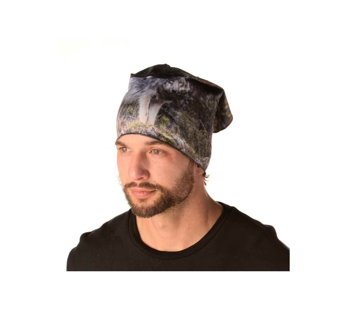 This is an image of man wearing a photo of a grey wolf on a head and neck band worn as a kerchief. The background is of evergreen trees and grey bushes, while the wolf head is full and fluffy in various tones of grey and white with beautiufl yellow eyes looking directly at you.