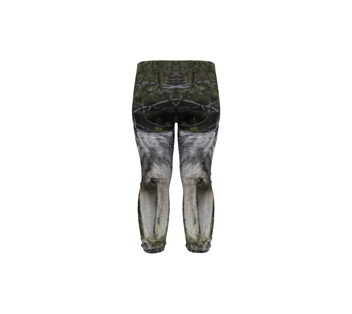 This is a rear profile of a photo of a wolf on a pair of infant leggings. It has one wolf head image on the side of each leg. The background is of evergreen trees and grey bushes, while the wolf head is full and fluffy in various tones of grey and white with beautiufl yellow eyes looking directly at you.