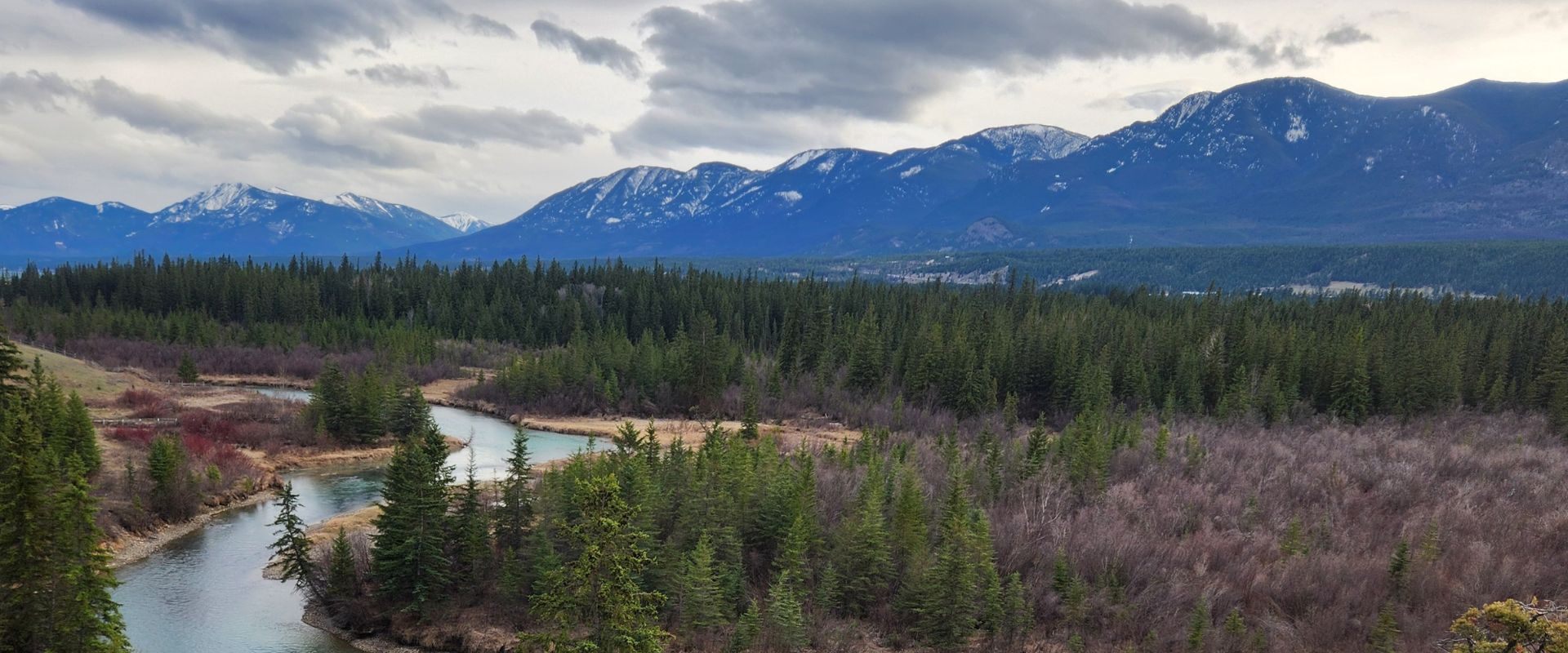 From the top of a hill we see the Columbia Valley below with its winding river and towering mountains.