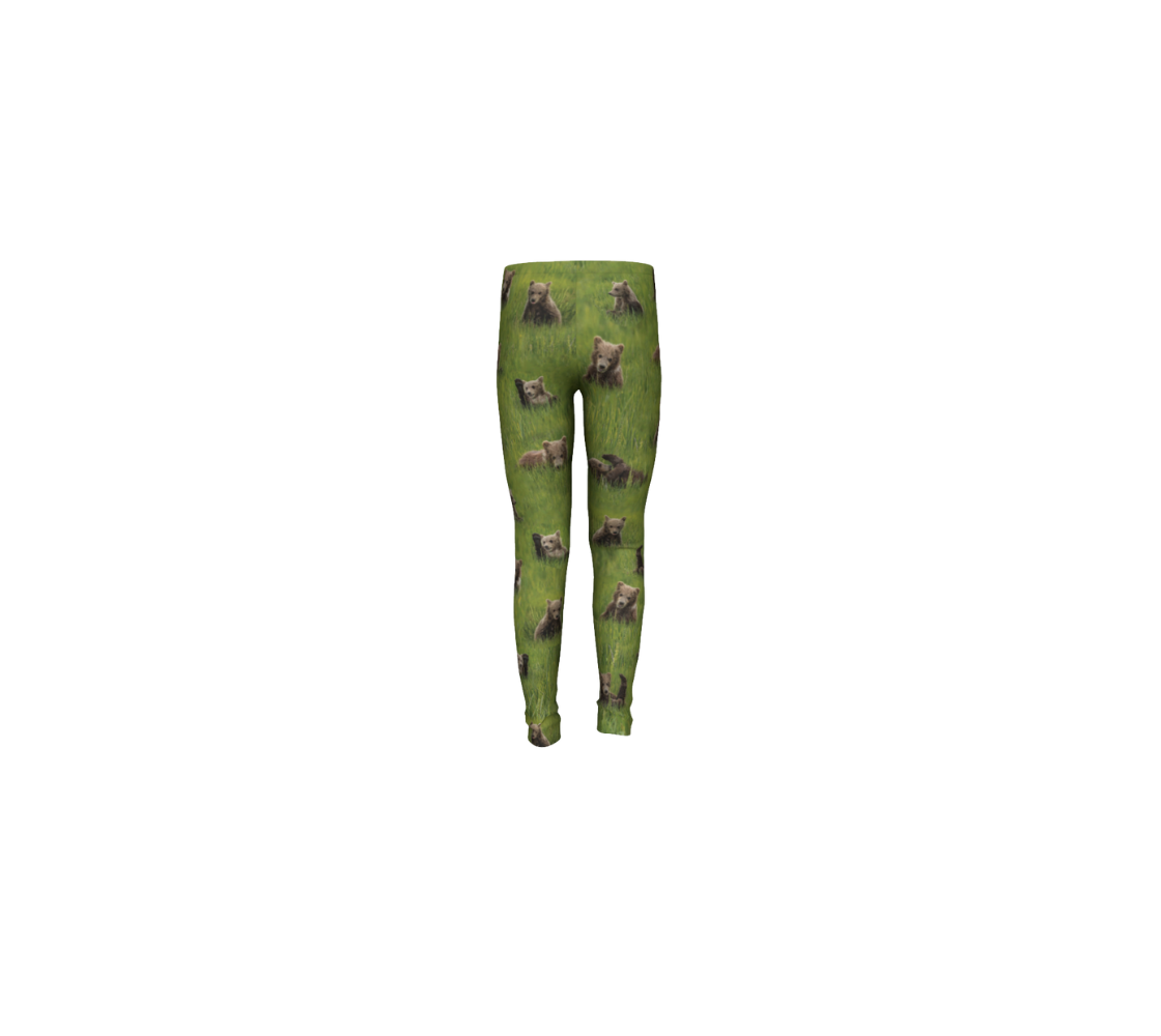 This is a rear profile of a pair of kids leggings featuring a collage of photos of little bear cubs playing in the grass. The background is bright green grass with little light brown colored bear cubs scattered throughout the leggings.