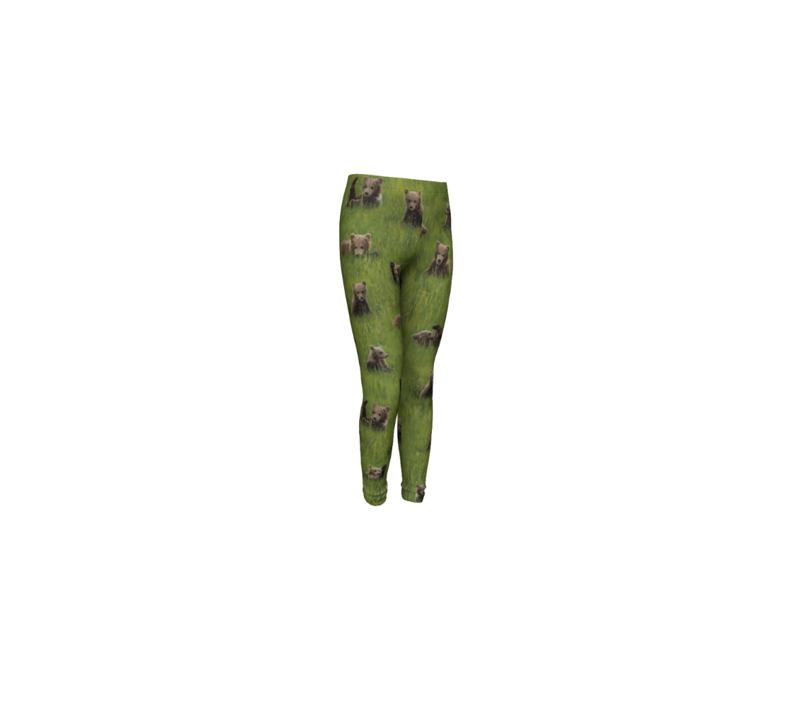 This is a front profile of a pair of kids leggings featuring a collage of photos  of little bear cubs playing in the grass. The background is bright green grass with little light brown colored bear cubs scattered throughout the leggings.