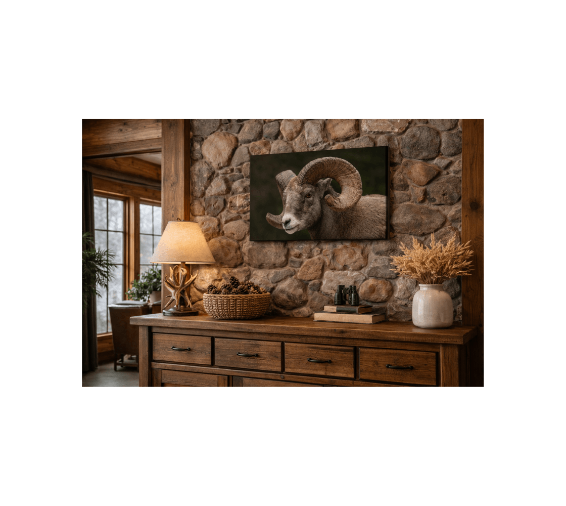 A stone wall with a canvas print of a bighorn ram from our wildlife photography hanging above wooden side broad table. 