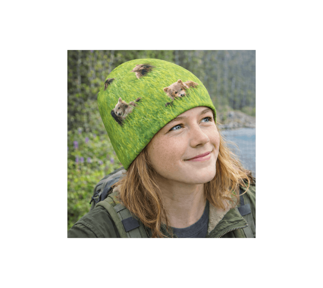 A young girl wearing a brown bear cubs bamboo-lined beanie from our wildlife photography standing by a river.