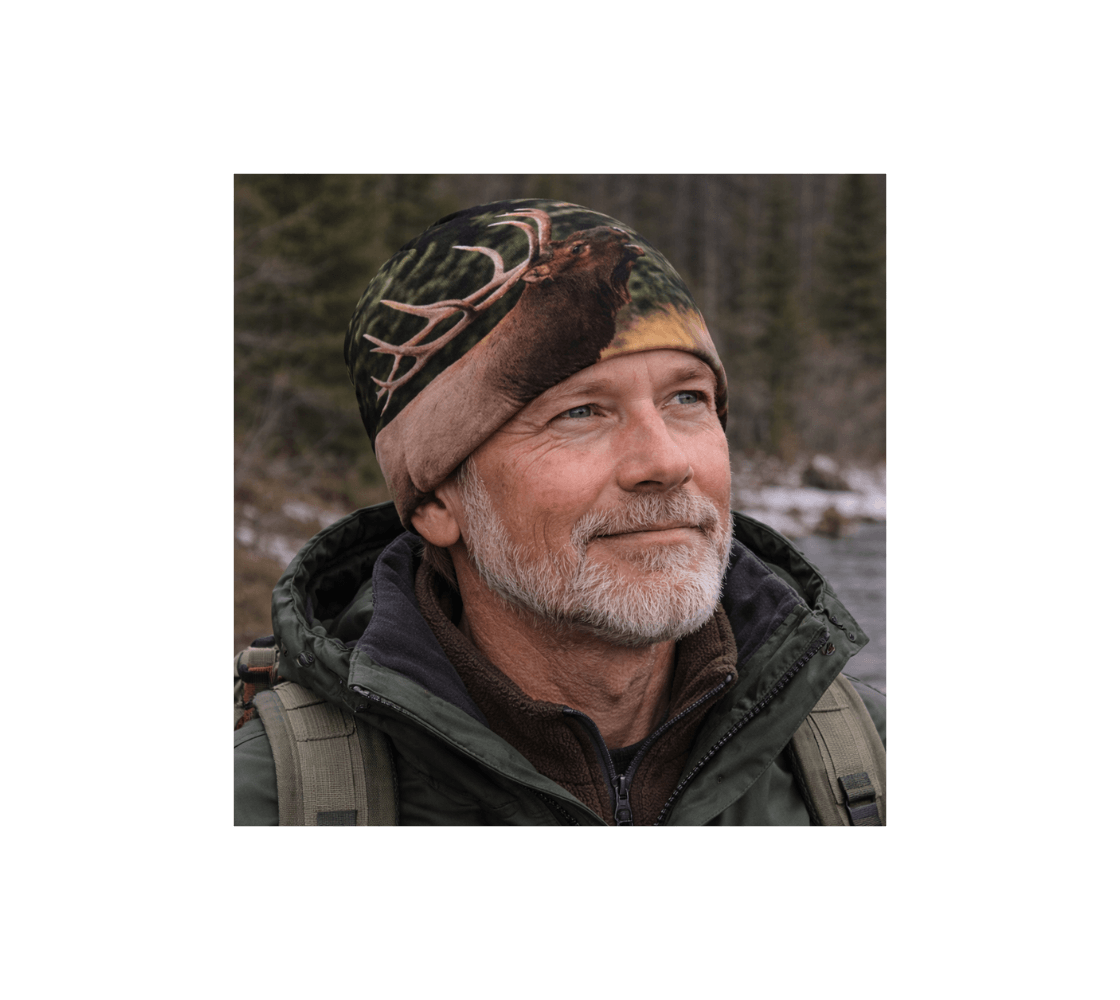 A older man wearing a bull elk bamboo-lined beanie from our wildlife photography standing by river. 