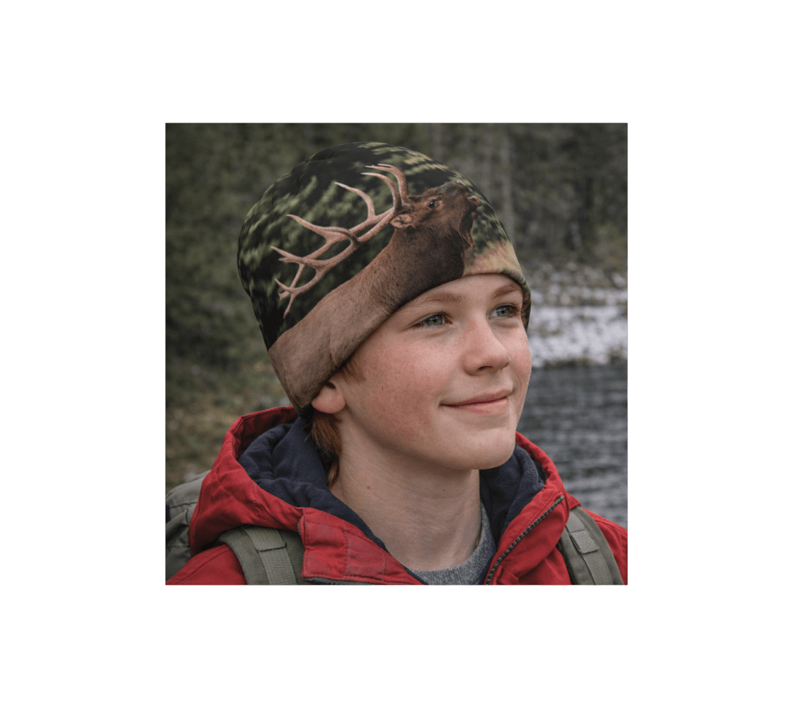 A young boy wearing a bull elk bamboo-lined beanie from our wildlife photography standing by river.