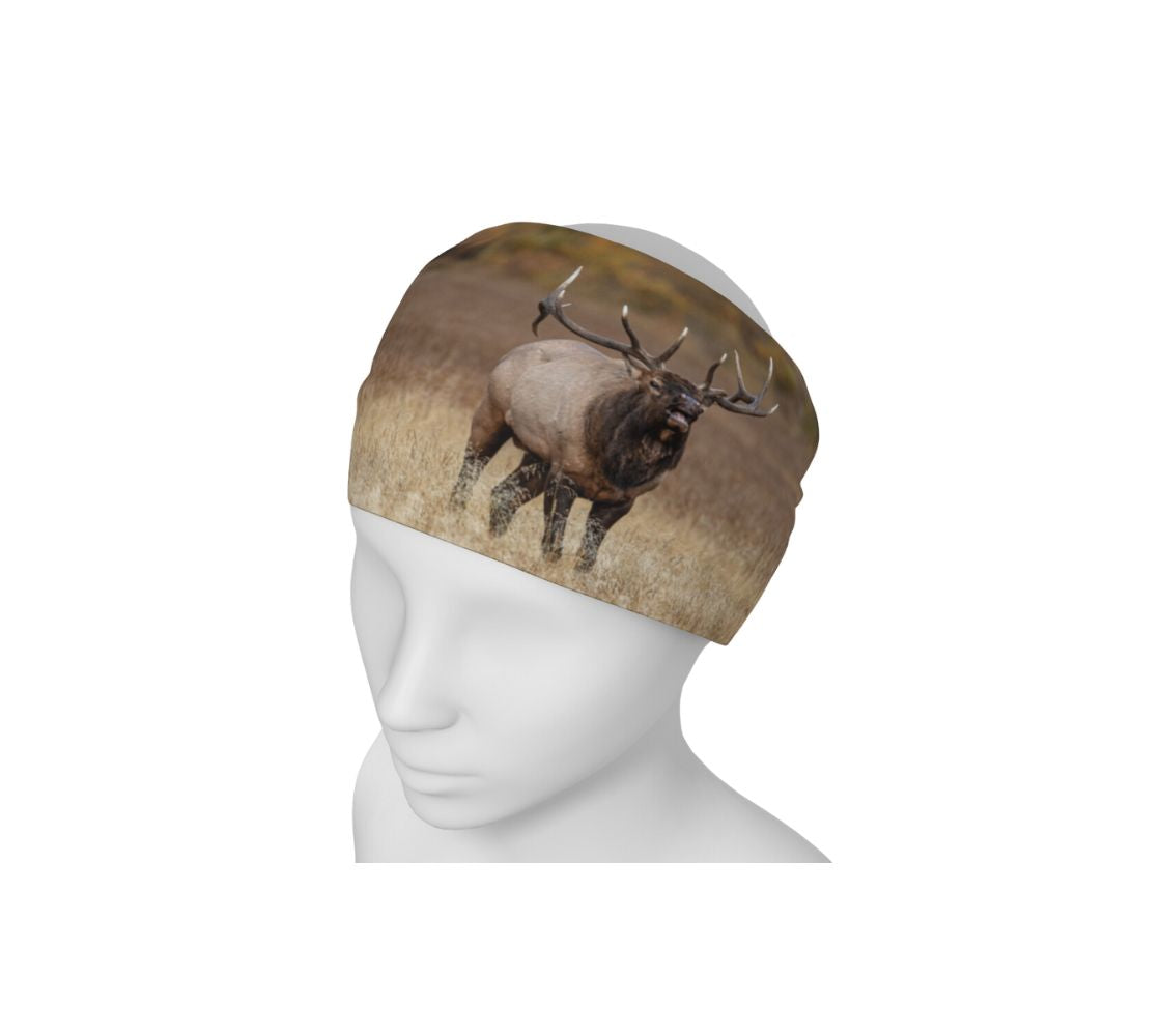 This is a photograph of a bull elk bugling on a head and neck band worn as a headband on a mannequin. The background is blurred yellow dead grass. The dark brown and tan colored elk with its large antlers is raising its head as it bugles out its mating call.
