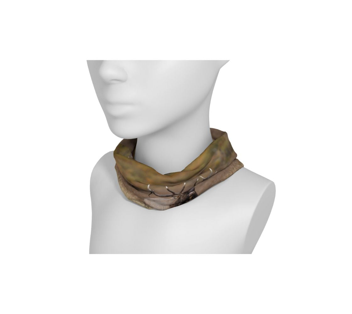 This is a photograph of a bull elk bugling on a head and neck band worn as a neckband on a mannequin. The background is blurred yellow dead grass. The dark brown and tan colored elk with its large antlers is raising its head as it bugles out its mating call.