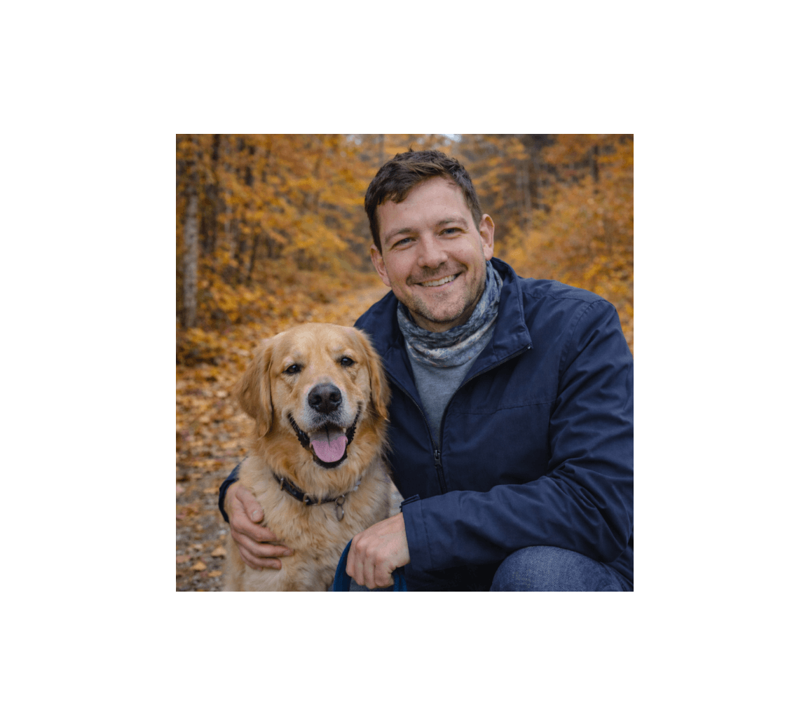 Man kneeling beside his dog wearing a bull moose head and neck buff from our wildlife photography around his neck in a autumn forest.