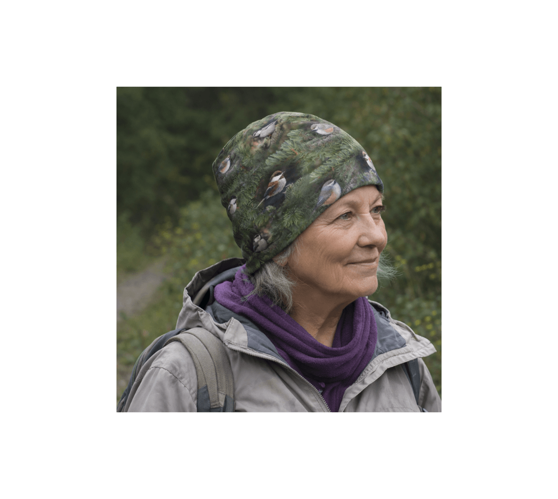 A elderly woman wearing a chickadee bamboo-lined beanie from our original wildlife photography in a forest setting.