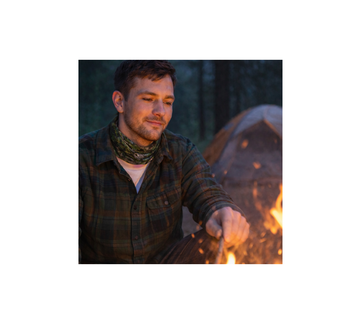 Man sitting by a campfire wearing a head and neck buff with image of great grey owl around his neck.