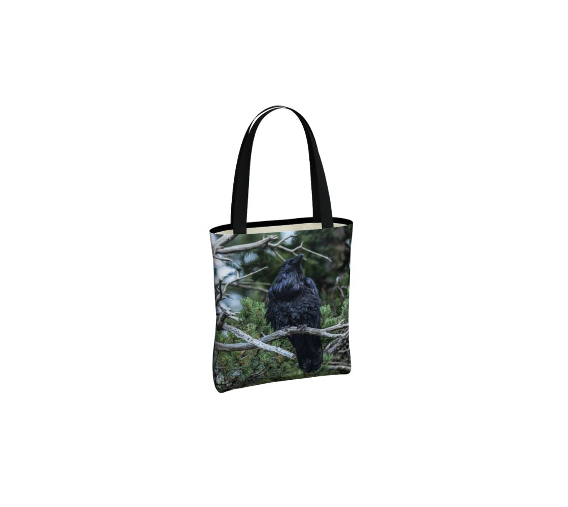 A small reusable tote bag with an image of a raven design with a green background.