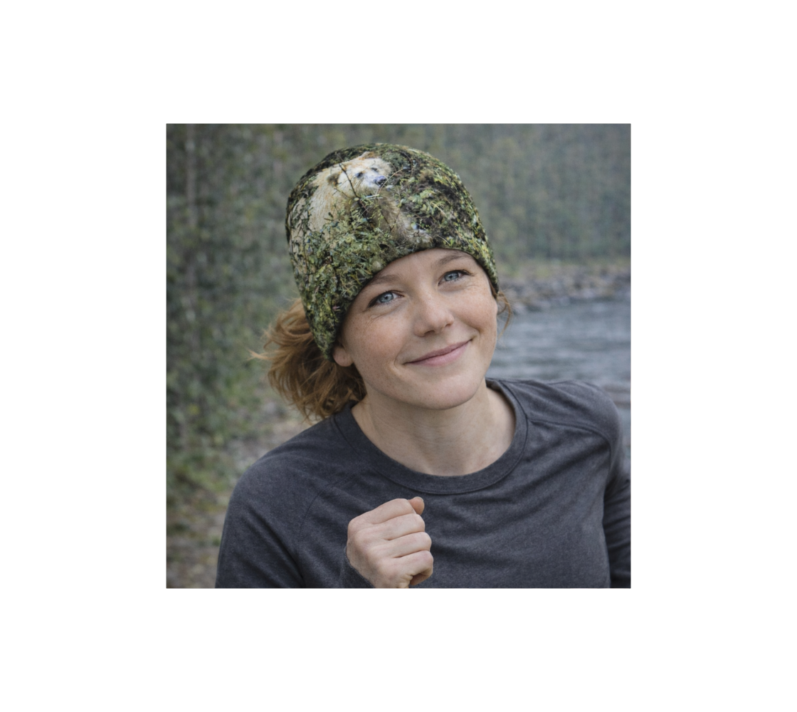 A young woman walking by river wearing a bamboo-lined beanie with an image of spirit bear design with a green background.