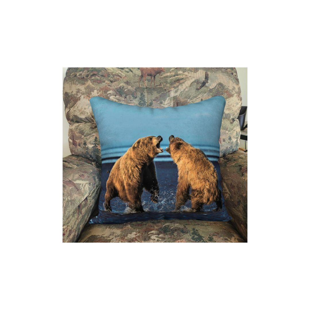 This 18 x 18 inch plush velveteen cushion cover features two female Alaskan brown bears squatted down roaring at each other. The cushion cover background is blue sky, lines of blue ocean out running cross and dark blue sand. This image is of a cushion cover on a pillow form in a chair.