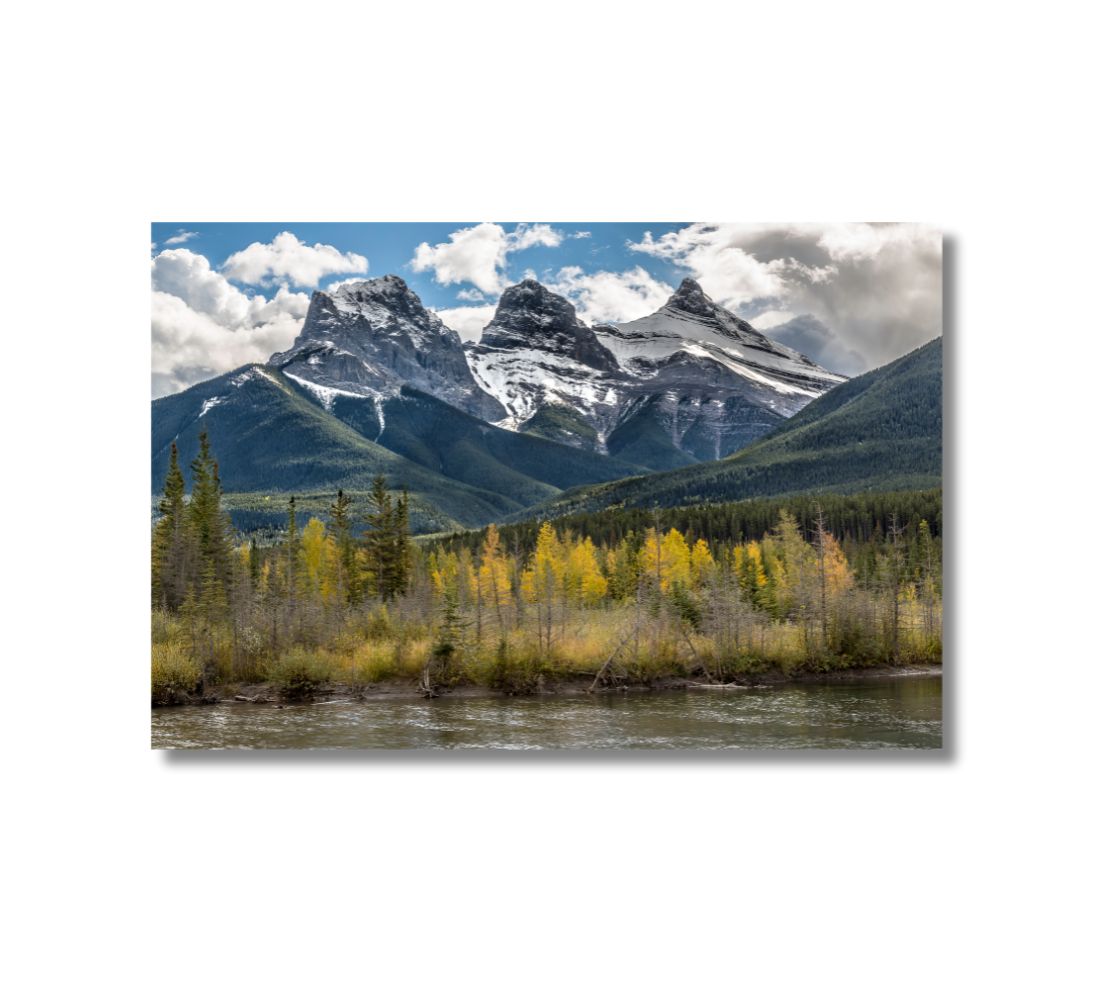 16 x 24 inch fade resistant canvas print. The Three Sisters photographed in autumn. Background green trees on the mountain, blue sky with white clouds and yellow trees in the foreground.