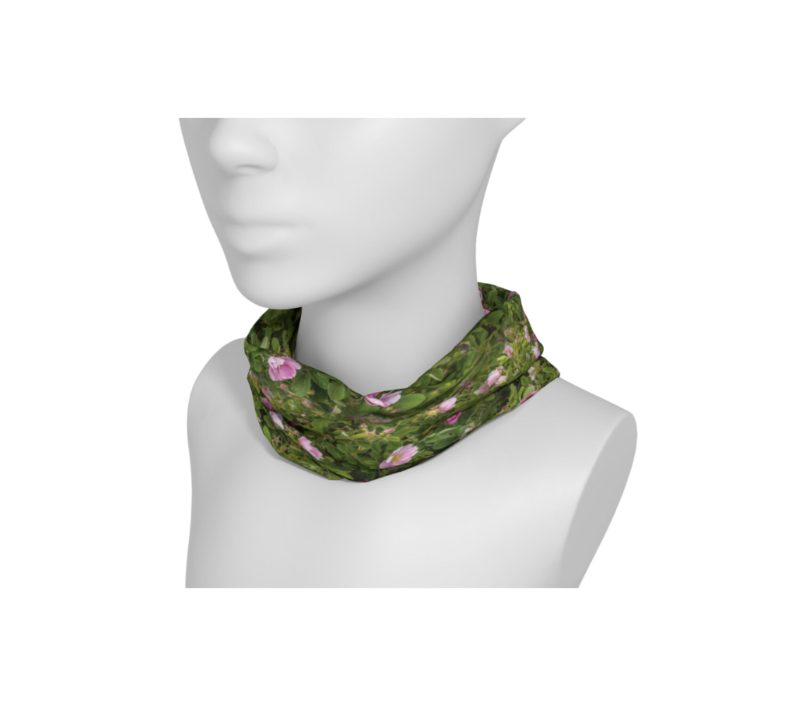 A mannequin head with a head and neck buff wrapped around the neck with collage of wild rose design with a green background .